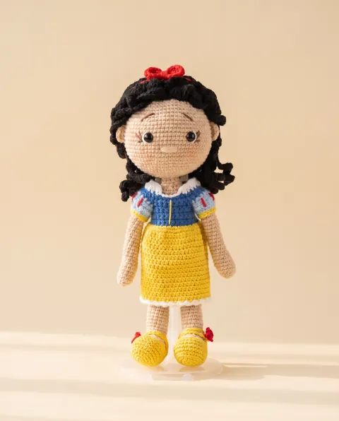 Muñeca de vestido azul y amarillo con moño rojo
