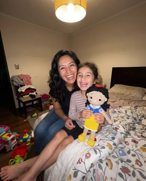 Mamá e hija riendo con la muñeca de vestido azul y amarillo