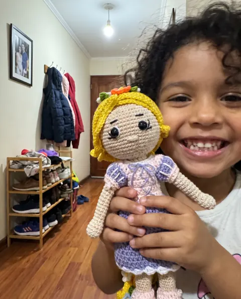 Niña sonriendo mientras abraza su muñeca de trenza dorada
